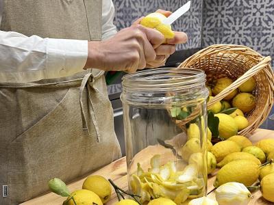 Persona pela limoni in cucina, riempiendo un barattolo.