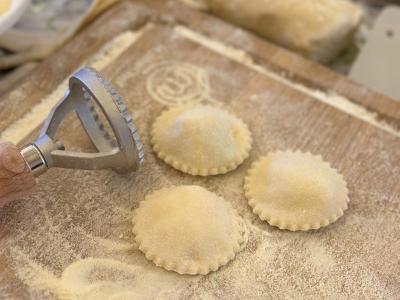 Preparazione di ravioli fatti in casa su un tagliere infarinato.