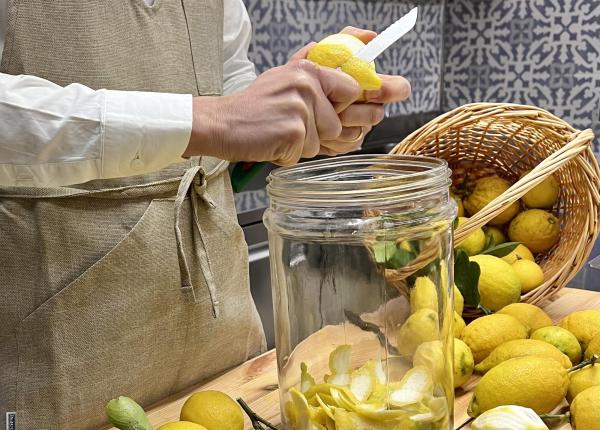 Persona pela limoni in cucina, riempiendo un barattolo.