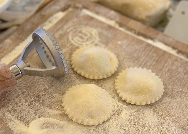 Preparazione di ravioli fatti in casa su un tagliere infarinato.